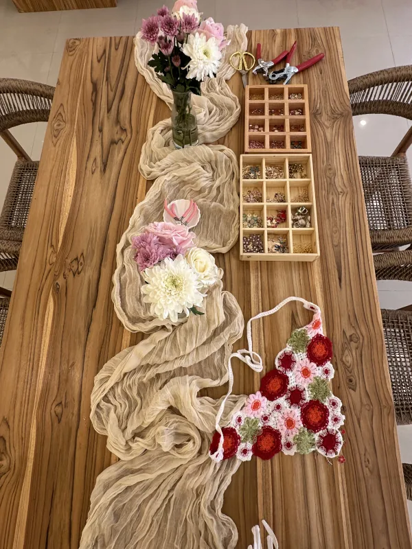 Workshop table in Canggu with a silk scarf, fresh flowers and boxes of charms ready for guests
